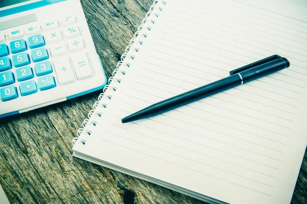 note paper,pen and calculator on wooden table