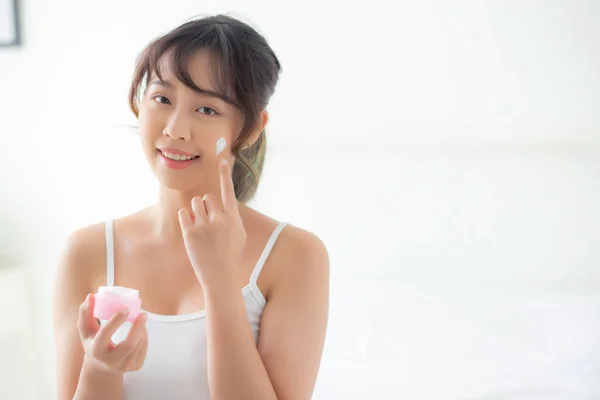 Bela jovem asiático mulher feliz aplicando creme ou loção com — Fotografia de Stock