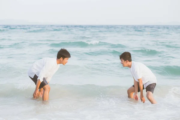 Гомосексуальный портрет молодой азиатской пары играть в воду на пляже с — стоковое фото