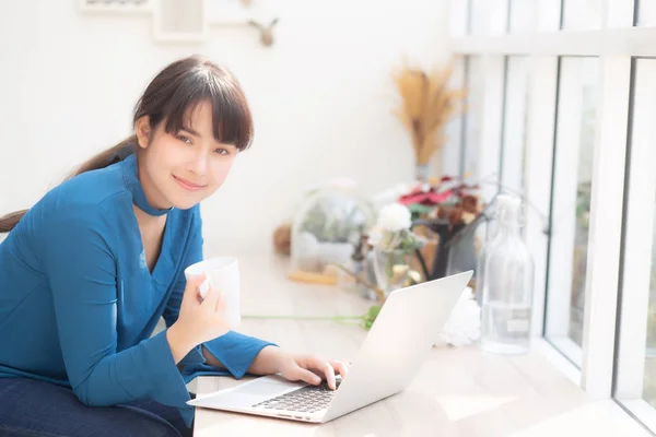 Mooie jonge freelance Aziatische vrouw glimlachend werken en op schoot — Stockfoto