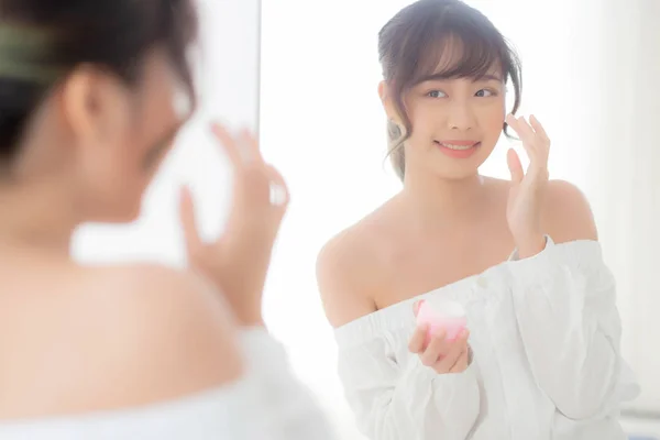Retrato bonito jovem mulher asiática aplicando creme hidratante — Fotografia de Stock