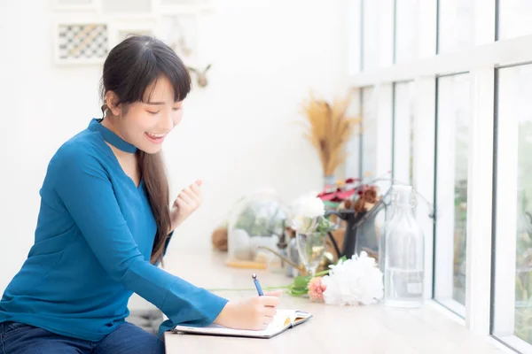 Beautiful portrait asian woman writer excited writing on noteboo — ストック写真