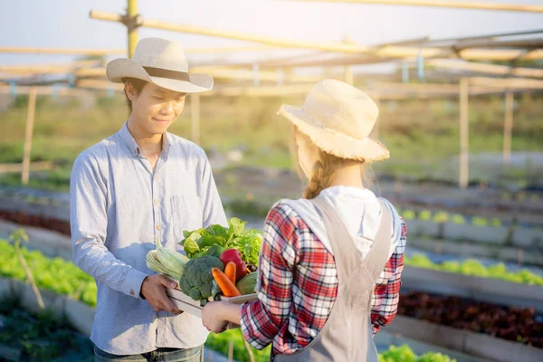 Krásná mladá asijská žena a muž drží čerstvé organické vegeta — Stock fotografie