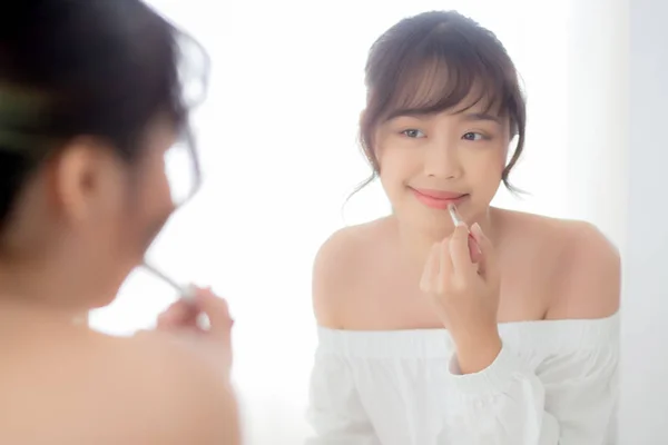 Retrato bonito jovem asiático mulher olhando espelho aplicando mak — Fotografia de Stock