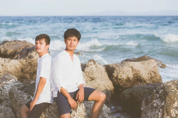 同性肖像画一对年轻的亚洲夫妇 夏天坐在岩石或石子上拥抱在一起 亚洲人快乐地出去观光休闲 在海上度假愉快地放松 这是法律概念 — 图库照片