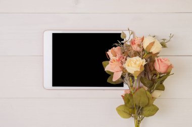 Anneler Günü veya Sevgililer Günü 'nde tablet boş ve çiçek ahşap masa pastel tonunda, dekorasyonla romantik, masa başı, tatil konseptiyle şenlikli.
