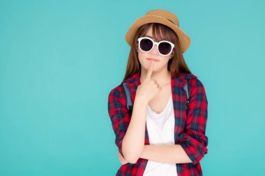 Güzel bir portre. Genç Asyalı kadın güneş gözlüğü takıyor ve şapka takıyor. Sırt çantasından gülümsüyor..