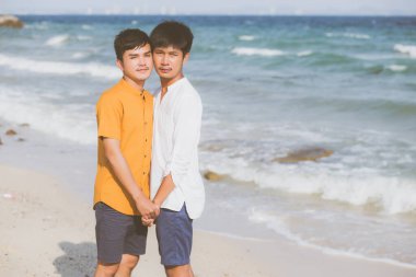 Homoseksüel portre genç Asyalı çift yazın plajda yan yana duruyorlar, Asyalı gey tatil için denizde el ele tutuşuyorlar ve denizde romantik ve mutlu bir tatil geçiriyorlar, yasal konsepti olan Lgbt.