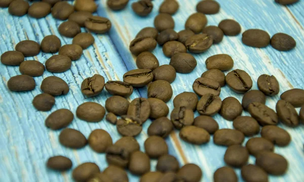 Kahverengi kahve çekirdekleri mavi ahşap masada.