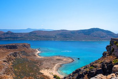 Dağların arasındaki sessiz bir koyda kumlu bir sahil, tepeden manzara.