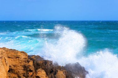 Mavi gökyüzüne çarpan dalgalardan fışkıran su.