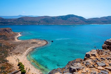 Dağların arasındaki sessiz bir koyda kumlu bir sahil, tepeden manzara.