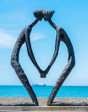 Sahilde arkasında bir gemi olan iki aşığın modern heykeli.