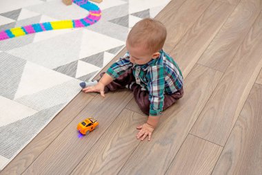 Çocuk oyun odasında yerde oturup oyuncaklarla oynuyor.