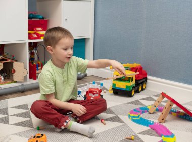 Çocuk oyun odasında yerde oturup oyuncaklarla oynuyor.