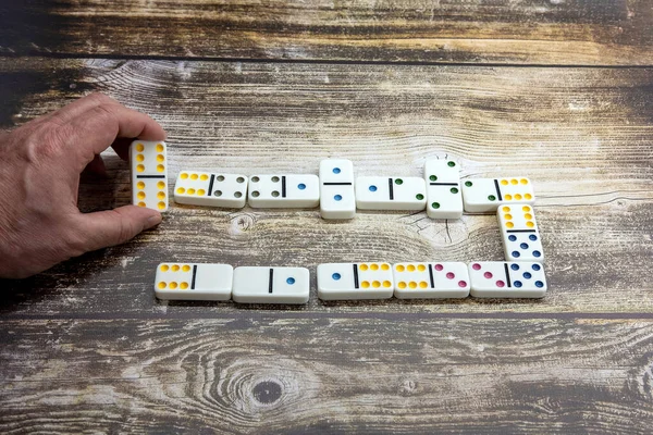 Spela domino på ett träbord en mans hand — Stockfoto