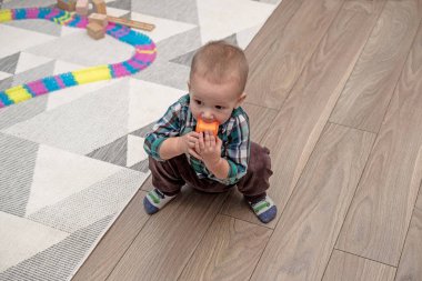 Çocuk oyun odasında yerde oturup oyuncaklarla oynuyor.