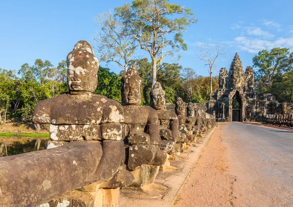 Köprü ve yol Angkor Thom ve yüzleri girişinde, Siem Reap, Kamboçya koruyan taş devlerin Güney kapıdan.   