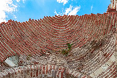 Nesebar, Bulgaria, July 23, 2012. the ruined dome of the old church. half of the dome is visible sky. Stone facade of the church. Ceramic facade inserts. Typical brick and stone masonry, authentic patterns.