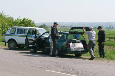 Ukraine, May 27, 2011. An officer inspects the trunk of a red car. The driver is watching.