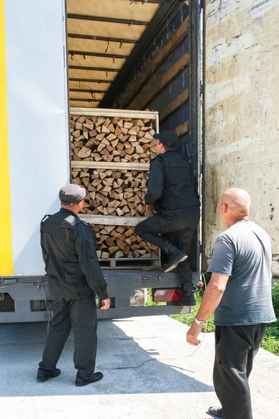 customs officers inspect a truck with lumber. two officers inspect, the driver observes