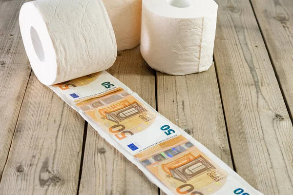 roll of toilet paper and euro money, on wooden background. concept