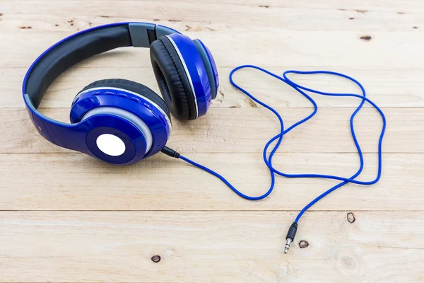 Blue headphones on wood desk.