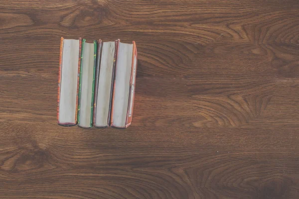 Old books standing on wooden table in vintage tone — Stock Photo, Image