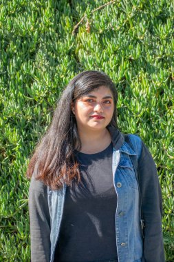 Latin ya da Hindu görünümlü tombul kadın parkta yürüyor.