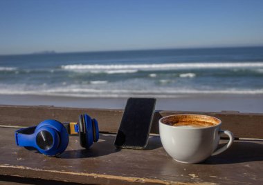 Plaj terasındaki bir barda nefis bir kahve. Rahatlatıcı bir atmosferde. Tatillerde, kulaklıklar ve cep telefonlarıyla.