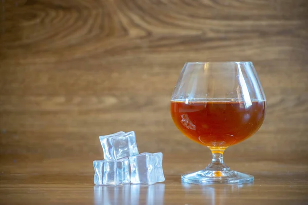 Composition with glass with delicious whiskey next to ice cubes. on oak boards — 스톡 사진