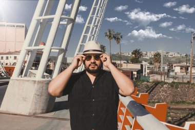 Fötr şapkalı yakışıklı Meksikalı tombul adam havacı gözlüklerini takıyor.