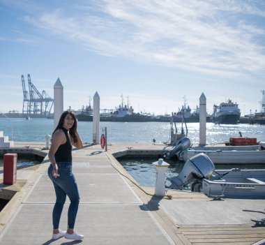 Güzel Meksikalı kız denizin önündeki iskelede yürüyor.