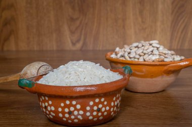 Tahta tahtaların üzerinde pirinç taneleri ve ahşap el yapımı kaşık olan Meksika tarzı kil kaplar.