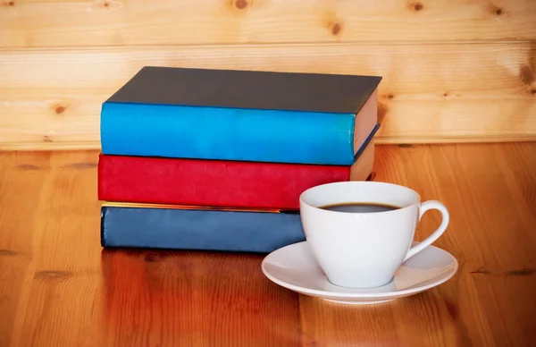 Книги и чашка кофе на деревянном столе на деревянном фоне — стоковое фото