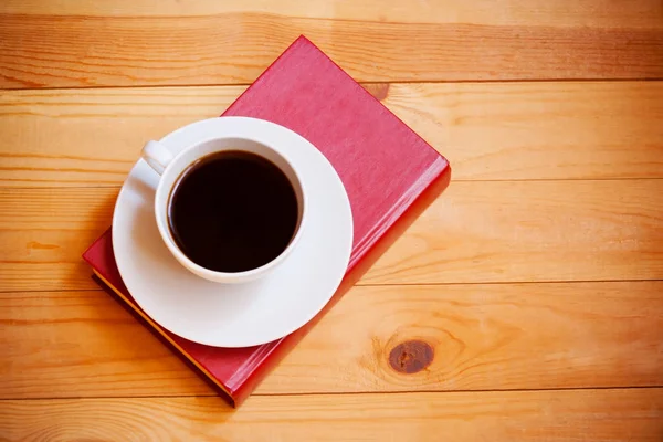 कॉफी कप आणि लाकडी पार्श्वभूमीवर पुस्तक. शीर्ष दृश्य — स्टॉक फोटो, इमेज