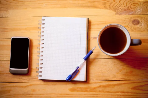 Notebook, tazza di tè e smartphone su sfondo di legno — Foto Stock