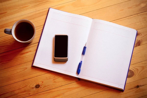 Kopp te, penna, öppnade arrangör och smartphone på trä bakgrund — Stockfoto