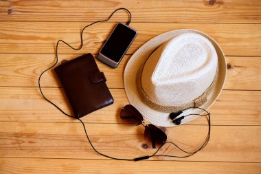 Şapka, cüzdan, smartphone, kulaklık ve ahşap arka plan üzerinde güneş gözlüğü. Gevşeme ya da tatil kavramı