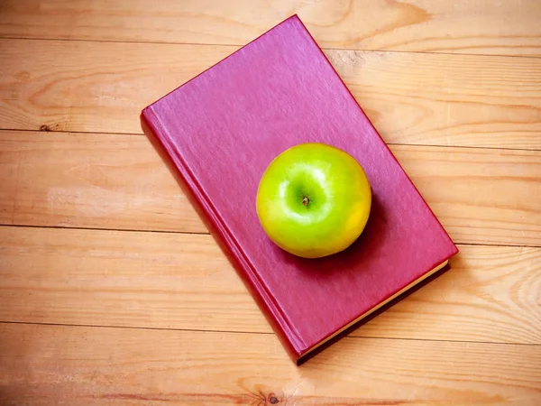 Apple, és a fából készült háttér könyv. Szemközti nézet — Stock Fotó