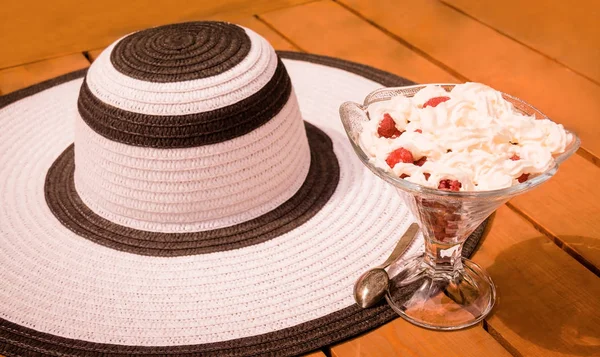 Tigela de vidro com framboesa e chantilly e chapéu de verão. Foco seletivo — Fotografia de Stock