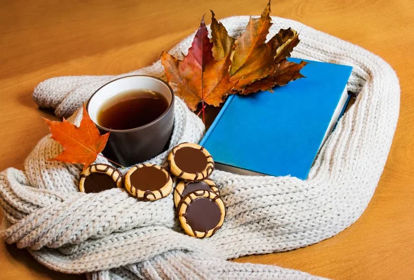 Tazza di tè, libro, sciarpa e biscotti sul tavolo di legno — Foto Stock