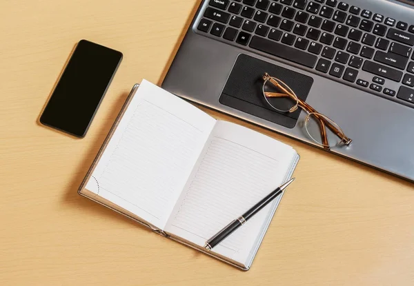 Office skrivbord med laptop, öppnade planner och smartphone. Ovanifrån — Stockfoto