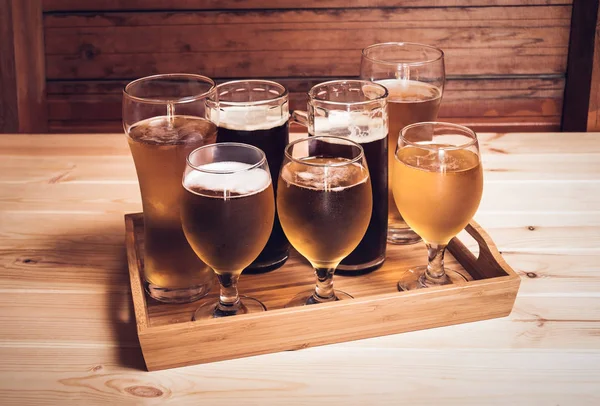 Vasos de cerveza y tazas de cerveza en la mesa de madera. Enfoque selectivo. Estilo vintage — Foto de Stock