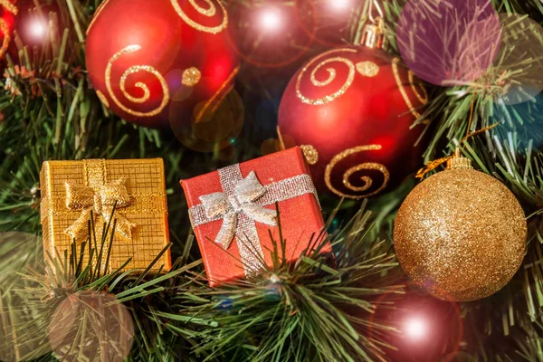 Bolas de Navidad rojas y doradas y regalos en el árbol de hristmas. Enfoque selectivo en regalos . — Foto de Stock