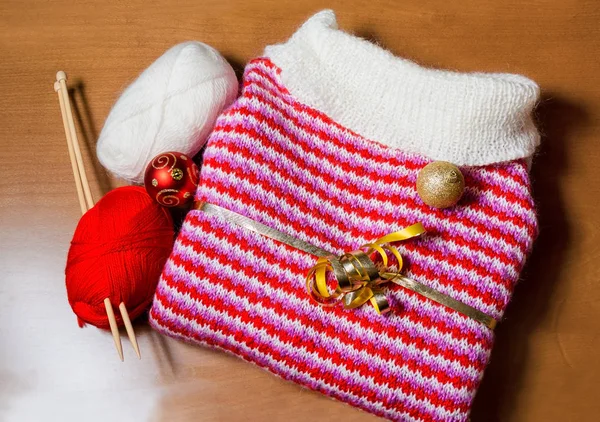 Теплый красный и белый вязаный свитер и рождественский бал на деревянном фоне . — стоковое фото