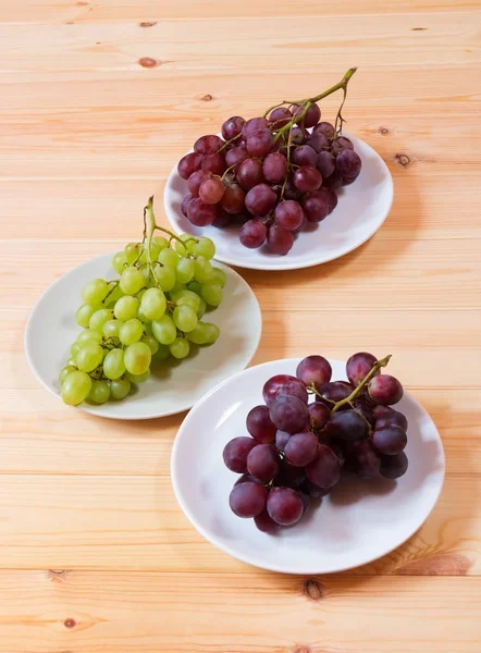 Uvas verdes e vermelhas na mesa de madeira . — Fotografia de Stock