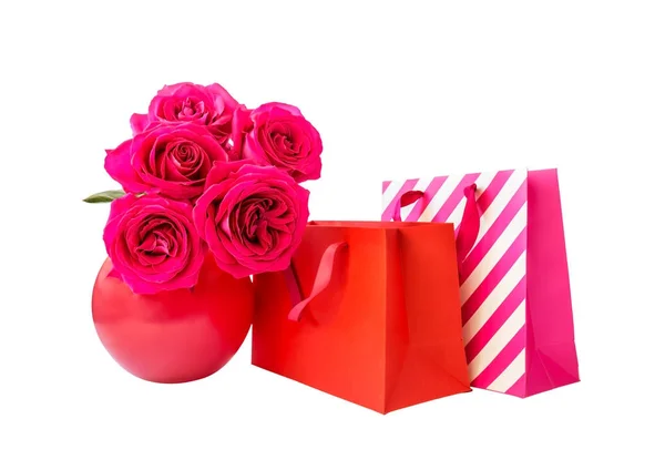 Πολύχρωμες τσάντες για ψώνια και ροζ τριαντάφυλλα που απομονώνονται σε λευκό — Φωτογραφία Αρχείου