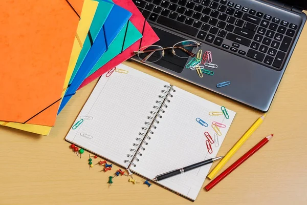 Office skrivbord med mappar, laptop, öppnade anteckningsbok och pennor — Stockfoto