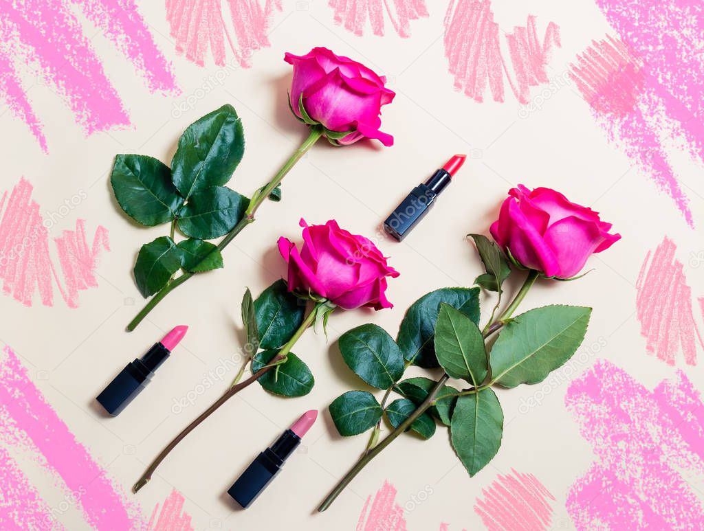 Colorful lipsticks and roses on beige background